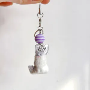 Handmade fluffy cat keychain with purple striped beads and heart charm on white background