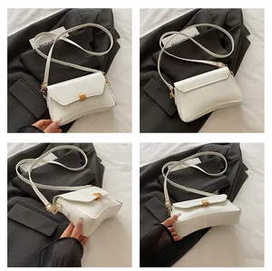 Détails d'un sac bandoulière en cuir blanc avec boucle en métal doré et design épuré