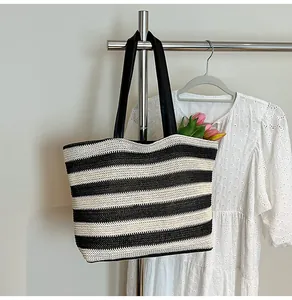 Detail of a large black and white striped woven tote bag with premium black leather straps