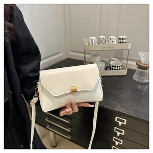 Gros plan du sac en cuir crème avec boucle dorée brossée dans un décor de café chaleureux