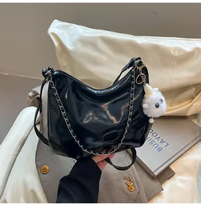 Detail of black glossy tote bag with silver chain and cute white plush puppy charm