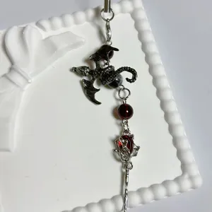 Bijou de téléphone dragon gothique avec perles en cristal rouge sur support blanc