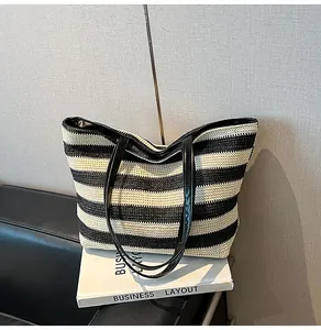 Close-up of black and white striped woven tote bag with glossy leather shoulder straps