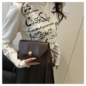 Détail d'un sac enveloppe en cuir marron foncé avec une boucle en métal doré vintage