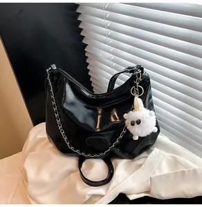 Glossy black tote bag detail featuring silver chain strap and cute white plush sheep charm