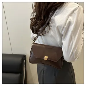 Détail d'un sac bandoulière marron foncé avec boucle dorée et coutures de qualité