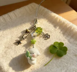Detail van pluche puppy hanger met klavertje en ster hanger op zachte witte stof