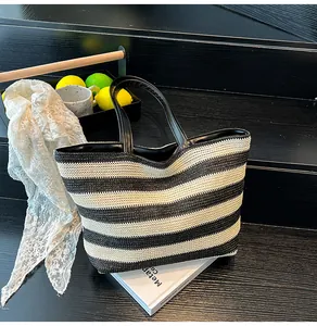 Detail of a large striped woven tote bag with leather handles and decorative lemons