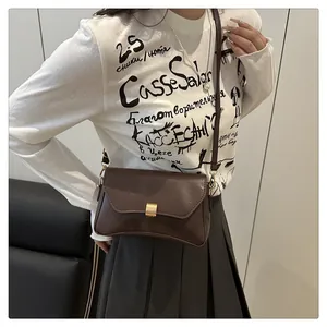 Détail du sac bandoulière en cuir marron foncé avec boucle métallique dorée élégante