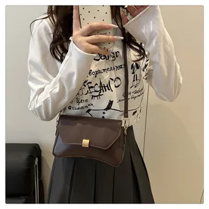 Détail de la boucle en métal doré sur un petit sac bandoulière marron foncé chic