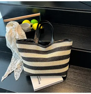 Close-up of a striped woven tote bag featuring black handles on a wooden step