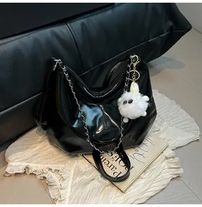 Detail of black patent leather hobo bag with silver chain and white fuzzy monster charm