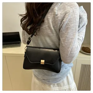 Détail d'un sac à bandoulière noir minimaliste avec boucle dorée sur l'épaule