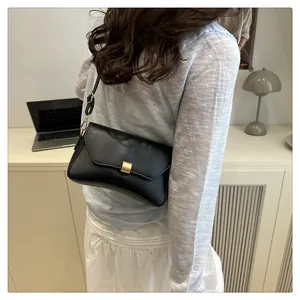 Gros plan d'un sac à bandoulière noir mat avec boucle dorée rectangulaire sur le rabat