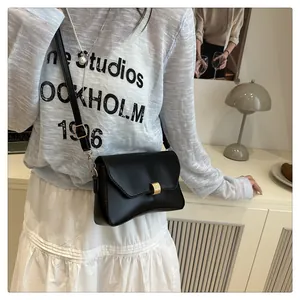 Détail du sac à bandoulière minimaliste en cuir noir avec boucle dorée et rabat lisse élégant