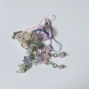 Dettaglio di ciondoli a medusa con perle a stella e lacci viola per borse e telefoni