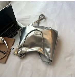 Silver metallic tote bag with chain strap styled with laptop and a white plush charm