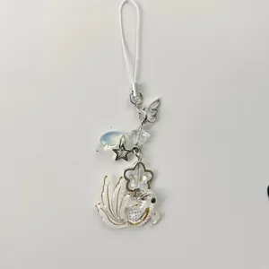 Macro view of koi fish pendant and star charms on a white beaded phone strap