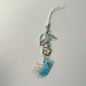 Detail view of handmade blue koi fish phone strap with silver stars and floral charms