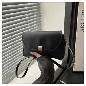 Détail d'un sac minimaliste en cuir noir mat avec fermoir carré en métal doré brossé
