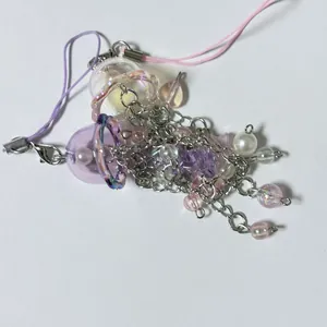 Dettaglio del ciondolo a medusa con perline viola iridescenti e nappe a catena d'argento