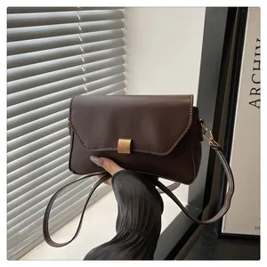 Détail du sac à bandoulière en similicuir marron foncé avec fermoir en métal doré brossé