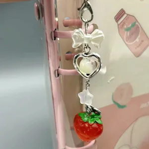 Sweet strawberry bow phone charm with heart and star pendants on a pink planner
