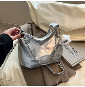 Detail of silver metallic tote bag with chain strap and cute plush charm pendant