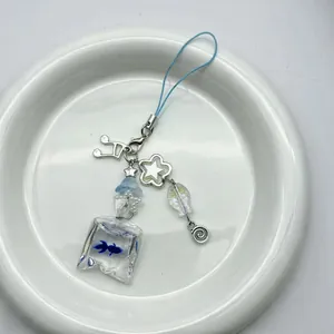 Blue fish bag pendant phone charm with metal music notes and star charms on white plate