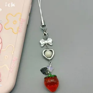 Detail of sweet strawberry phone charm with ribbon bow, heart beads, and love tag