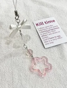 Détail d'un charme de téléphone fait main avec nœud blanc nacré et étoile rose