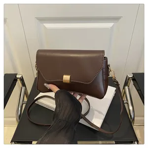 Détail d'un sac à main en cuir marron foncé avec boucle carrée en métal doré mat