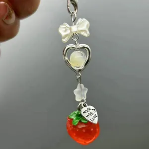 Detailed view of handmade bow and strawberry phone charm with stars and heart pendant