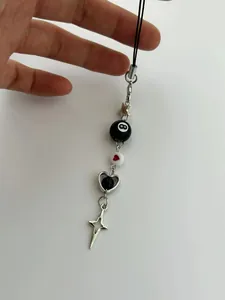 Macro shot of Y2K beaded charm featuring black 8-ball and silver heart star pendants