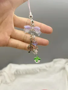 Detailed shot of pink beaded phone charm with lavender bow and metal clef pendant