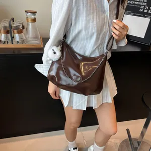 Fashionable dark brown tote bag with silver chain and plush charm in a cafe setting