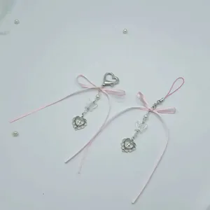 Detail eines rosa Satinband-Bogenanhängers mit weißen Perlen und silbernem Herzanhänger