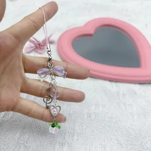 Pink and purple beaded phone charm with bow, musical note, and heart pendant detail