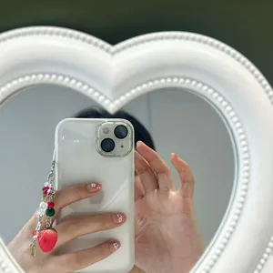 Detail of sweet strawberry phone charm with red beads and 3D bow on a white smartphone