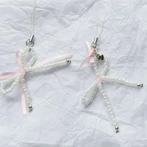Handmade pearl bow phone charm with pink ribbon and silver heart pendant on white crepe