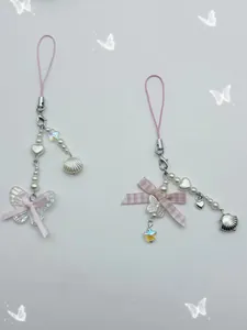Detail view of Y2K style bow phone straps with pearlescent beads and iridescent charms