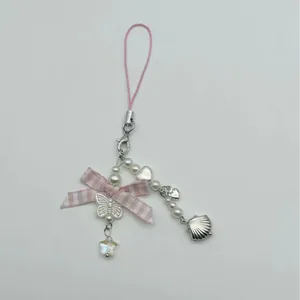 Pink bow phone charm with pearls and star pendants on a clean white background