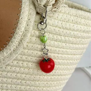 Cute tomato bag charm with green heart beads and silver star on a woven straw bag
