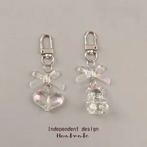 Handmade 3D bear and heart keychain set with iridescent bows on a grey background