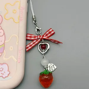 Detail of strawberry charm with red bow, heart pendant and resin strawberry drop