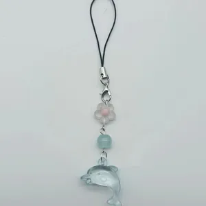 Detailansicht eines Ozean-Handyanhängers mit blauem Delfin und weißer Blumenperle