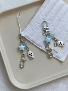 Detail of Y2K star and fish bead charms with lobster clasp on a white tray