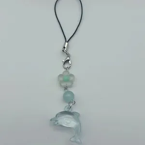 Detail des kreativen Delfin-Anhängers mit blauen Perlen und schwarzem Schlüsselband