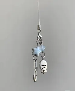 Close-up of cute fish pendant and star bead on a white minimalist braided strap