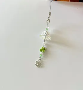 Detailed shot of handmade green clover charm with glass bell and pearl beads